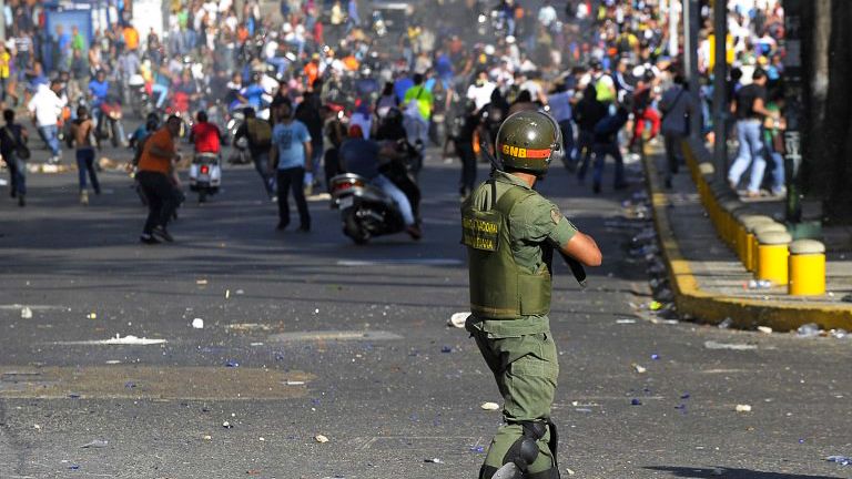 An armed policeman confronts protesters. 