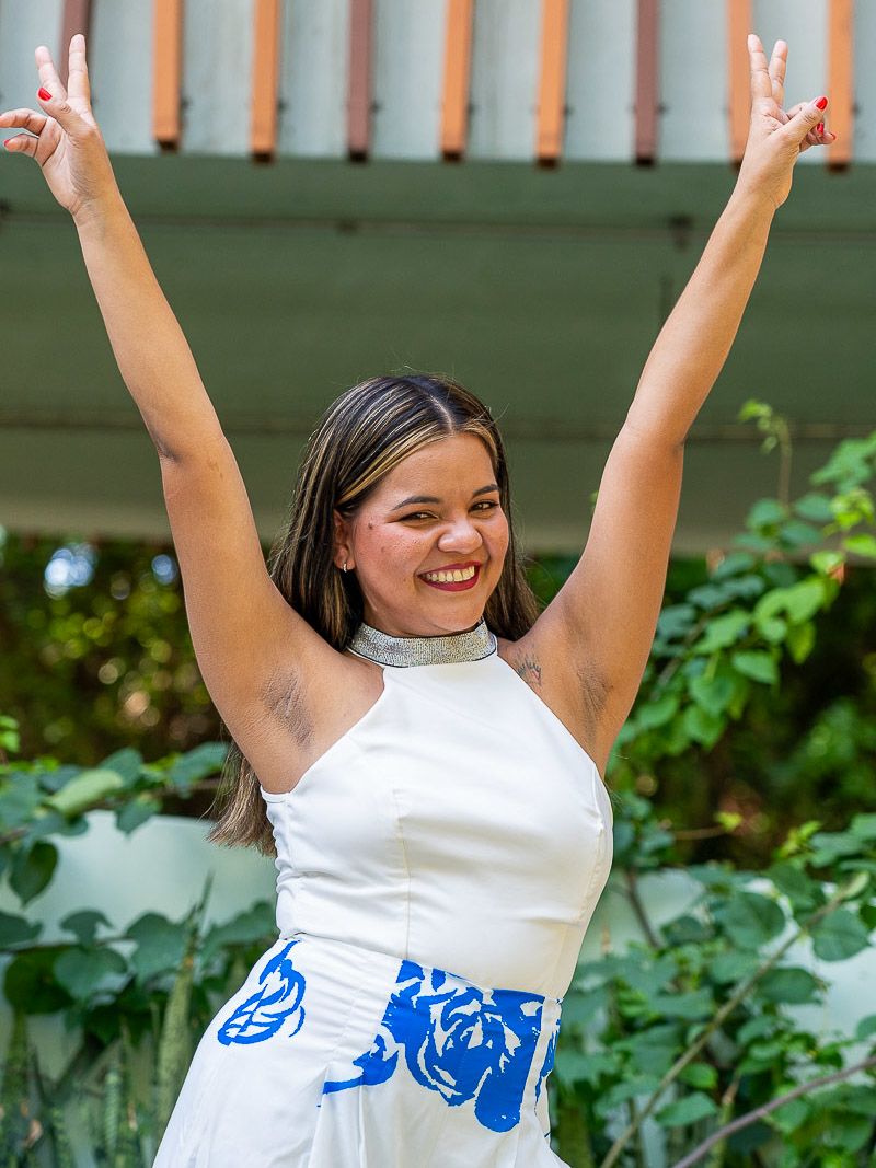 A young woman poses for a portrait with her hands in the air.