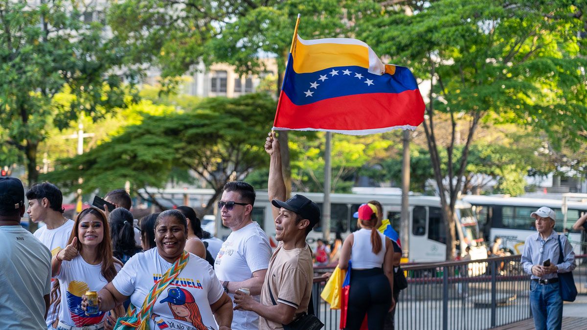 A family at a protest. A man holds a Venezuelan flag while whistling.